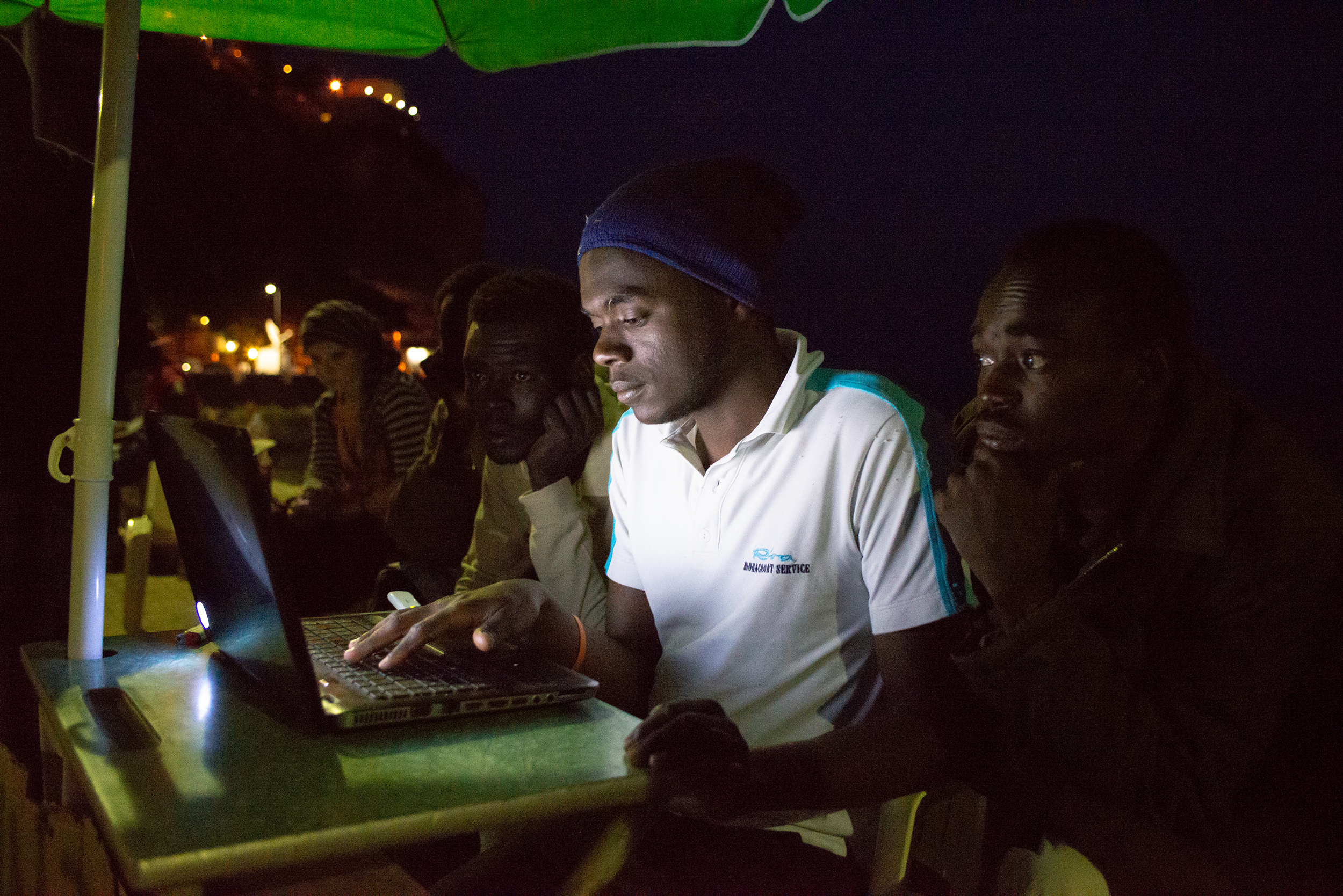 A man working on a laptop with a friend sitting nearby