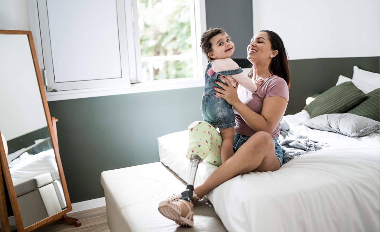 Mother with disability playing with baby girl at home © Getty Images