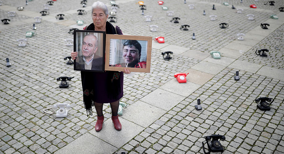 Fadwa Mahmoud holds portraits of her son and husband, who disappeared in 2012, as around 300 landline telephones placed by Syrian families stand at the Bebelplatz as a call to governments to do more to seek information about detained people in Syria, in Berlin, Germany August 28, 2021. REUTERS/Hannibal Hanschke