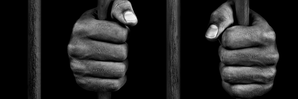 Hands of a prisoner on bars - stock photo - Credits: Getty Images