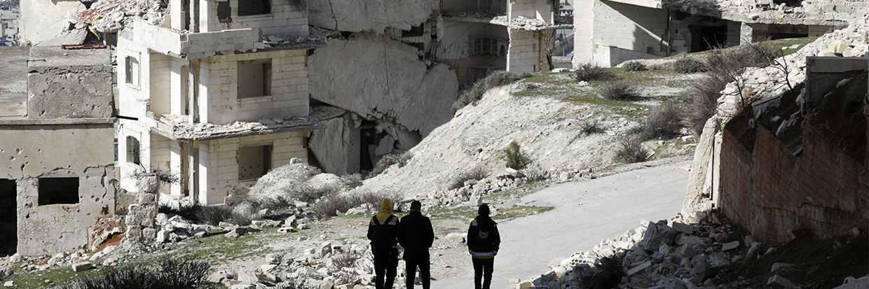 Plusieurs personnes marchent devant des bâtiments détruits à Jabal al-Arbaeen, tenu par les rebelles, dans la province d’Edleb, au sud de la Syrie, le 20 mars 2022. © Reuters