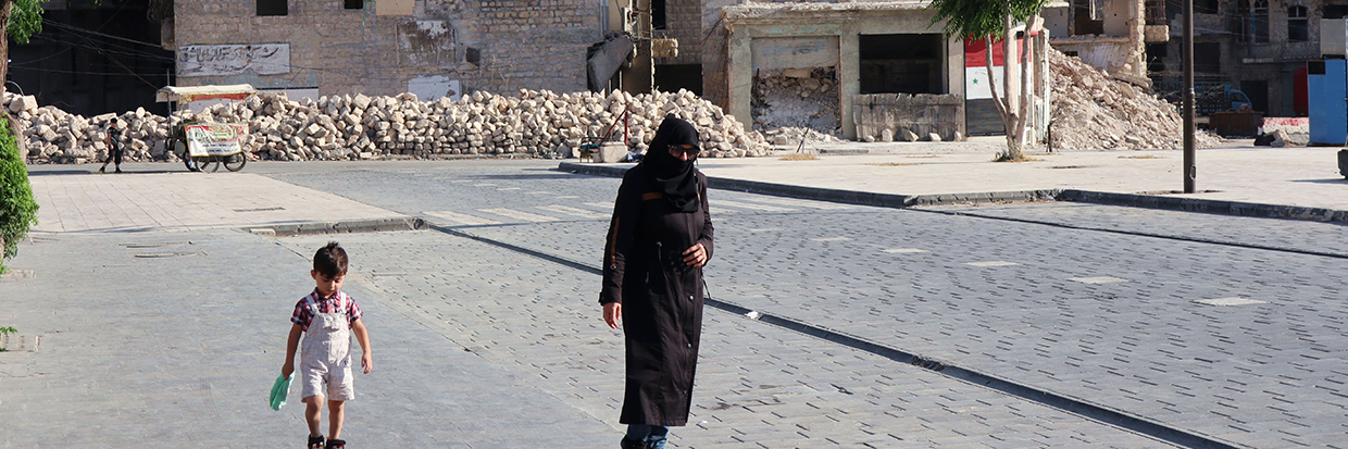 People walk past ruins in Aleppo, Syria, 17 June 2022 © Reuters