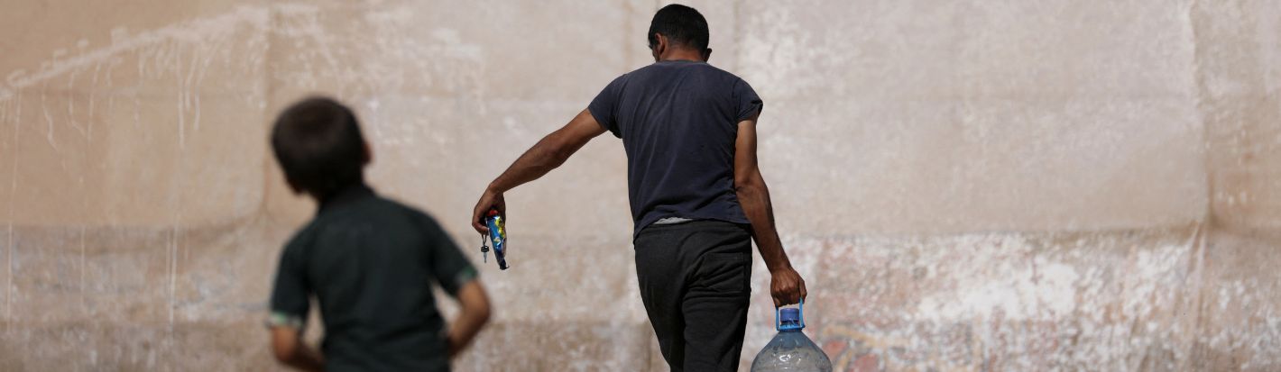 Un hombre lleva un contenedor de agua mientras pasa por delante de una tienda de campaña en un campamento para desplazados internos sirios, en el norte de Idlib, Siria, controlado por los rebeldes, el 25 de septiembre de 2022. © Reuters