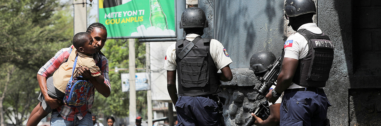 Un homme portant son fils cherche un abri en sortant de l’école alors que la violence des gangs fait rage à Port-au-Prince, Haïti, le 3 mars 2023. © REUTERS/Ralph Tedy Erol