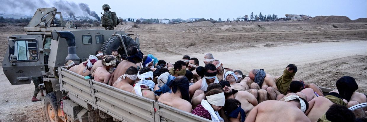 Soldados israelíes de pie junto a un camión cargado con detenidos palestinos sin camisa, durante el conflicto en curso entre Israel y el grupo islamista palestino Hamas, en la Franja de Gaza. 8 de diciembre de 2023. © REUTERS/Yossi Zeliger