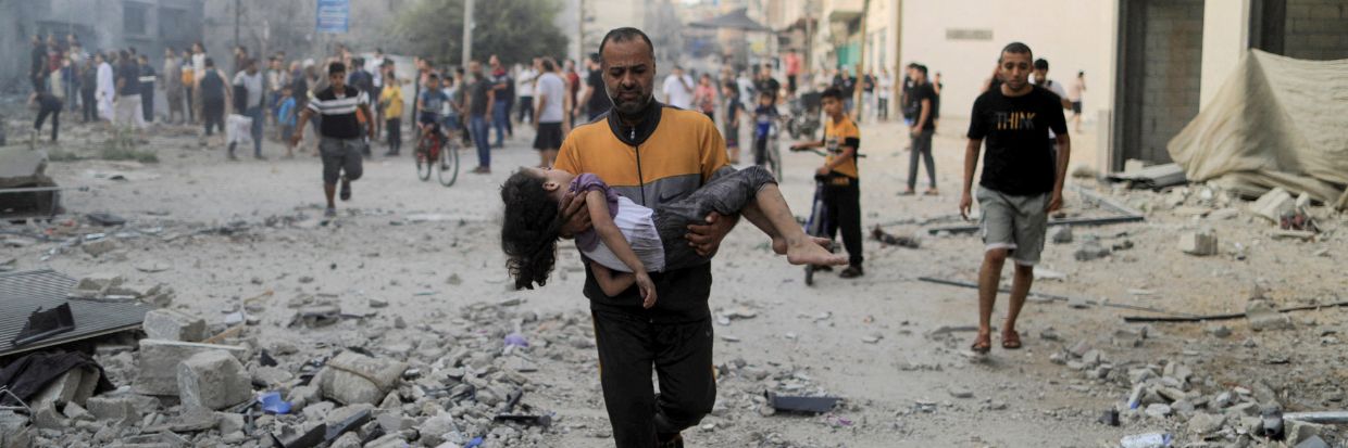 A Palestinian man carries a wounded girl at the site of Israeli strikes, in Khan Younis in the southern Gaza Strip October 14, 2023. © REUTERS/Yasser Qudih