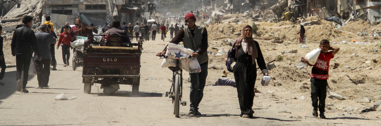 Des Palestiniens portent des sacs d’aide humanitaire tandis que d’autres ont des difficultés à obtenir leur part, sur fond de famine généralisée, alors que le conflit entre Israël et le groupe islamiste palestinien Hamas se poursuit. Photo prise à Gaza le 3 avril 2024. © REUTERS/Mahmoud Issa