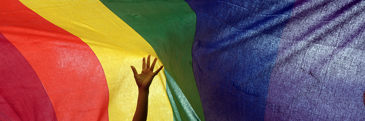 Un membre d’une minorité sexuelle indienne tend son bras au-dessus d’un drapeau arc-en-ciel lors d’une marche des fiertés à Kolkata, le 7 juillet 2013. Des centaines de militantes et militants LGBT ont participé au rassemblement pour réclamer l’égalité des droits sociaux et humains pour leur communauté. © AFP PHOTO/Dibyangshu SARKAR