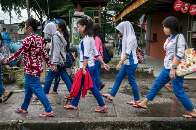 A group of young women migrant workers make their way through back alleys to get to work at a nearby hi-tech factory facility, Petaling Jaya, Malaysia, 28 November 2017. © UN Women