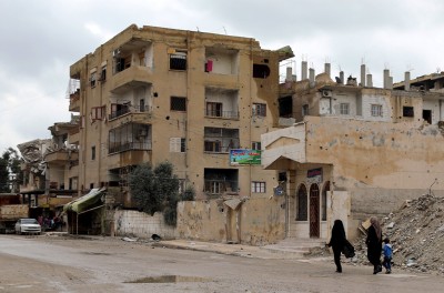 Two Syrian women walk next to destroyed buildings in central Raqqa city, Syria, 31 March 2019. © EPA-EFE/AHMED MARDNLI 