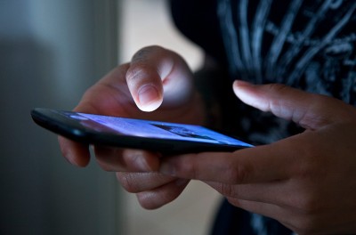 Hands holding a mobile phone. © Getty Images/Marco Piunti