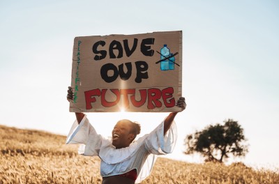 Woman standing in nature with a message to raise awareness against climate change © Getty/Leo Patrizi.