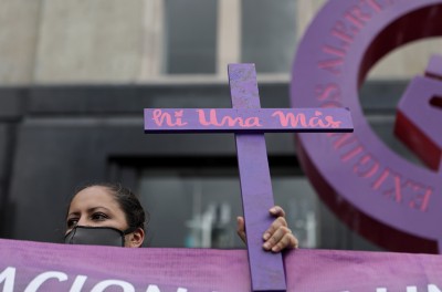 A woman holds a cross reading "no more missing" during a march demanding justice for the victims of gender violence and femicides in Mexico City, Mexico. © REUTERS/Raquel Cunha. 