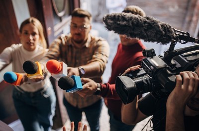 Group of people, female politician confronted by journalists with microphones © Getty 