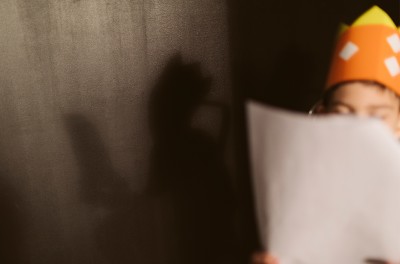 A child, whose face is hidden by a script he holds in his hands, during a theatre rehearsal. © Getty Images