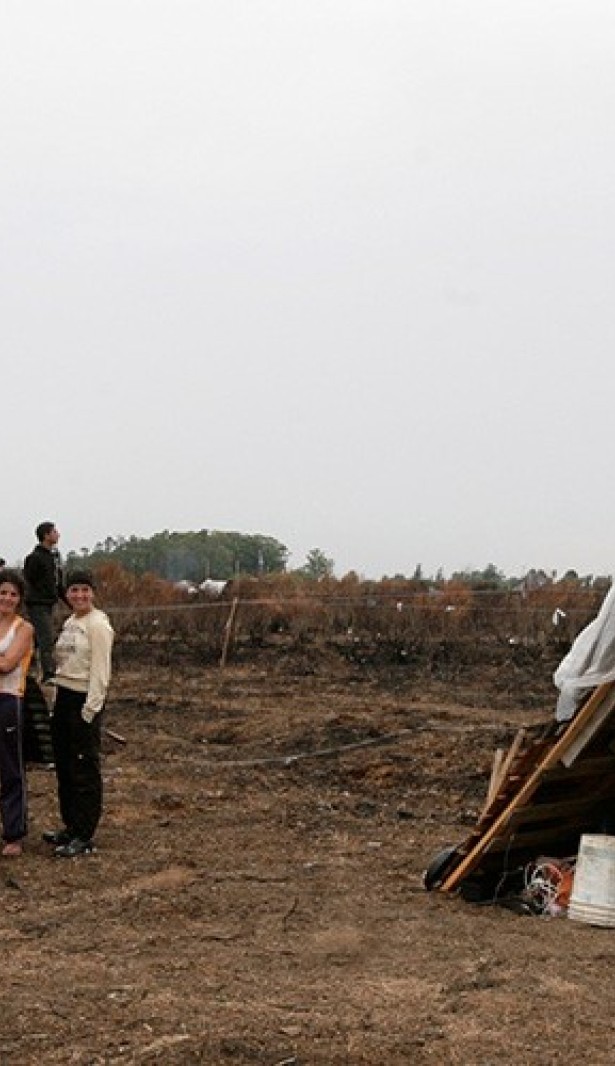 2011年1月19日，蒙得维的亚郊区，一些棚户区居民站在空地上的简易房旁。©路透社/Andres Stapff