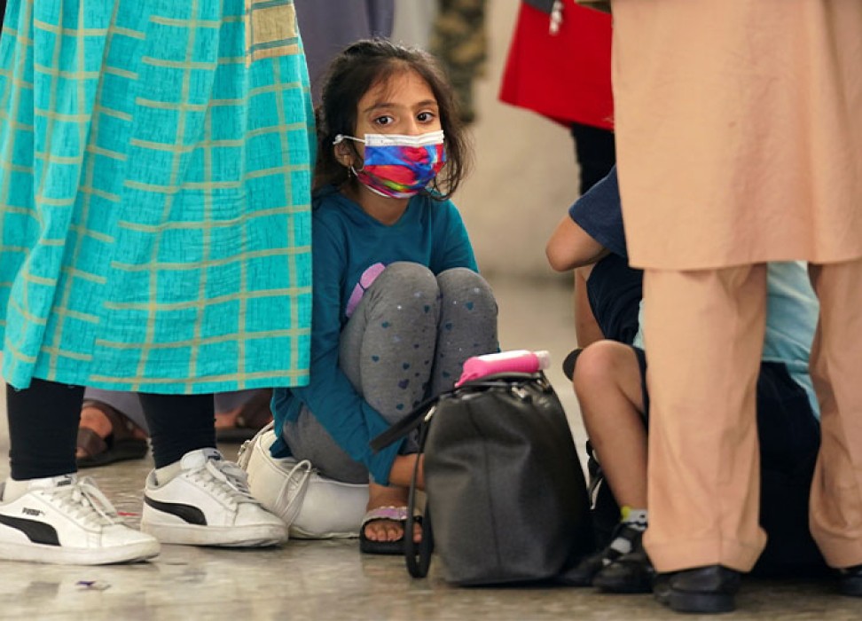 An Afghan girl waits with other refugees for a bus to take them to a processing center upon arrival at Dulles International Airport in Dulles, Virginia, U.S., August 26, 2021. REUTERS/Kevin Lamarque