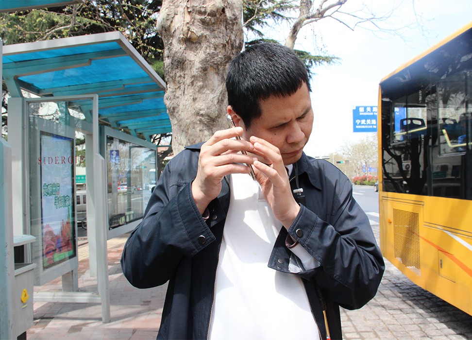 Un homme aveugle utilise une application mobile pour l’aider à prendre le bus à Qingdao, une ville de la province du Shandong, à l’est de la Chine, le 5 novembre 2019.