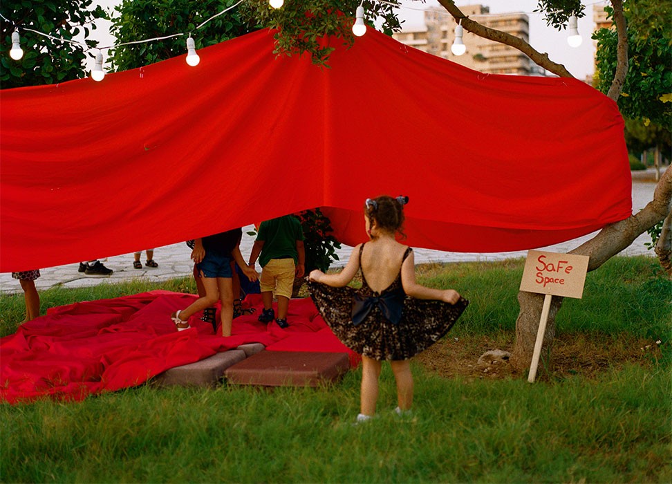 Una niña jugando frente a nuestro "espacio seguro" en Trípoli, Líbano, la primera ubicación del festival móvil Jeyetna en julio de 2021. Durante los eventos de Jeyetna, las mujeres pueden participar en círculos de debate en los que todas las mujeres y personas que menstrúan pueden compartir sus experiencias y expresar sus opiniones en un entorno libre y sin prejuicios. © Evelina Llewellyn