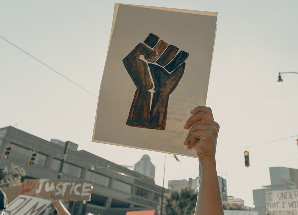 Une femme dans la foule tient une pancarte représentant un poing fermé, à Charlotte (Caroline du Nord), aux États-Unis, le 3 juin 2020. © Clay banks/UNSPLASH