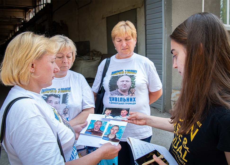 Olga Manukhina, dont le fils et le mari ont été arrêtés par des soldats russes, montre des photos de ses proches. © HCDH/Yevhen Nosenko