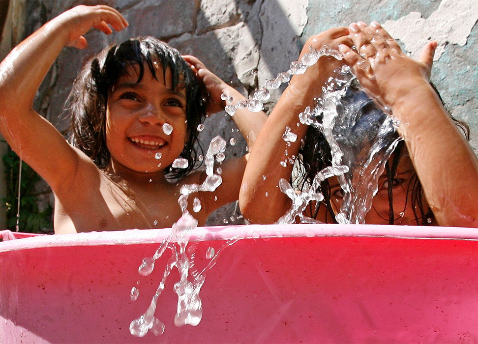 Roma children cool off in a tub of water in front of their house. © Credit –REUTERS/Ivan Milutinovic (SERBIA) 