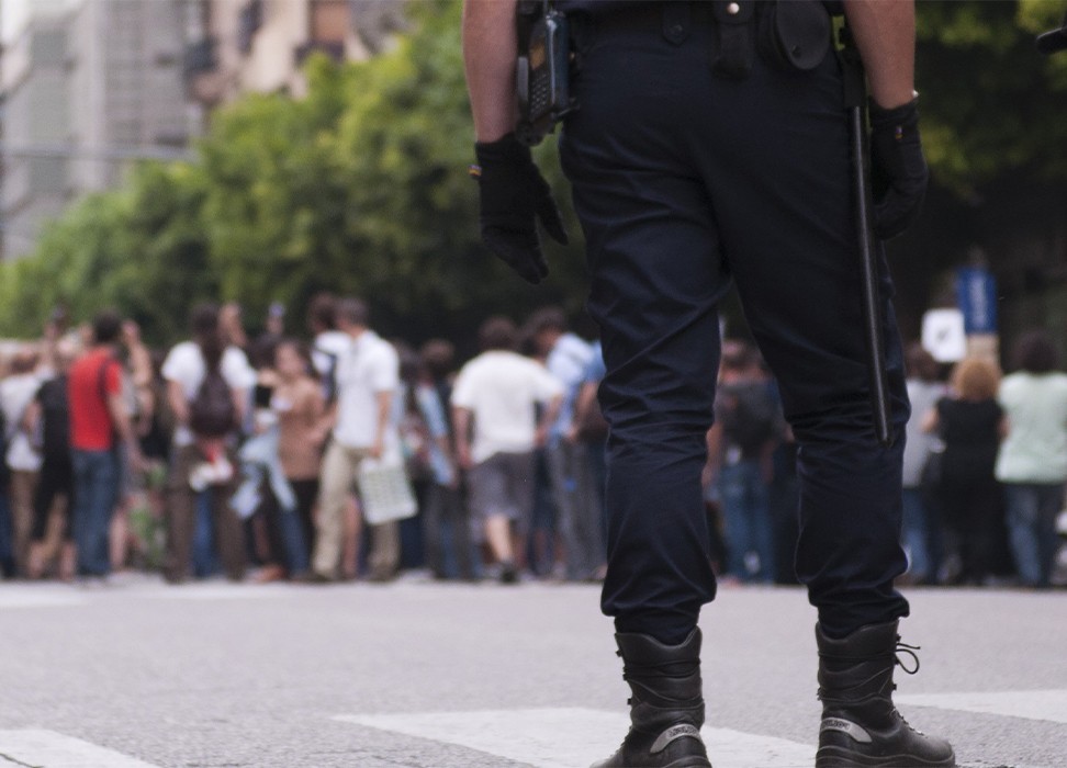 Dos agentes de policía observan a un grupo de manifestantes que protestan en la calle. © Getty Images/Lalocracio