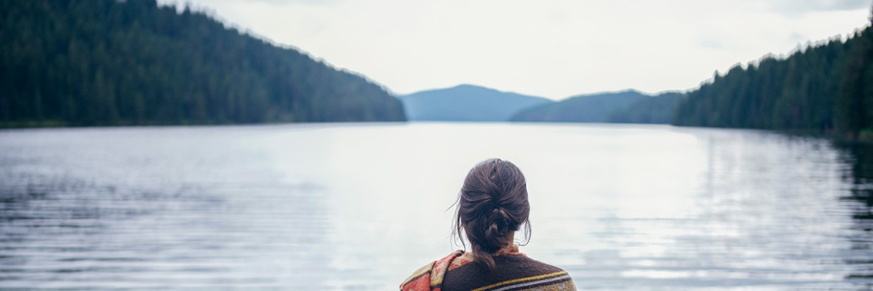 Woman standing in front of mountain lake 