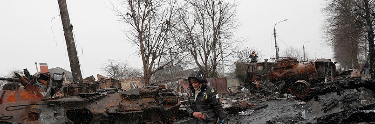 A Ukrainian woman walks pass destroyed Russian military machinery in the areas recaptured by the Ukrainian army in the city of Bucha, Ukraine, 03 April 2022. EPA-EFE/ATEF SAFADI.