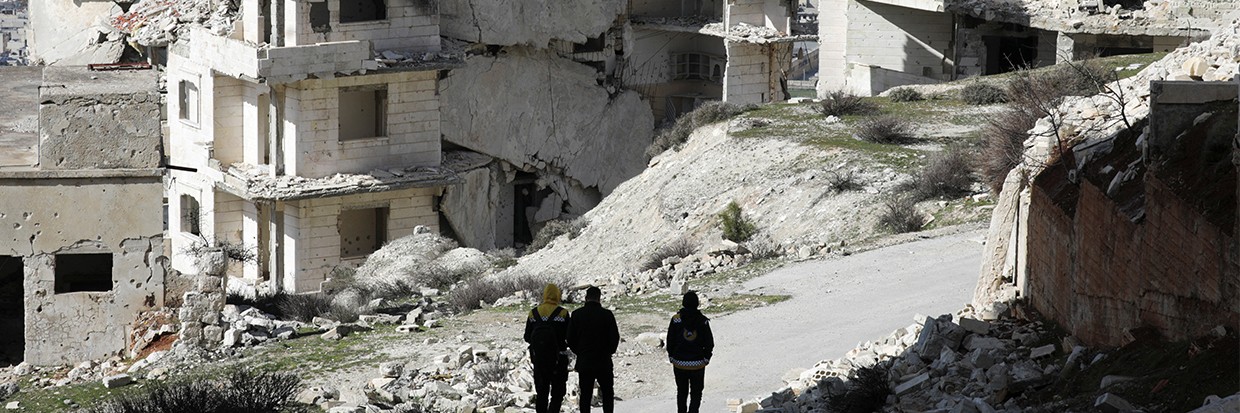 People walk past damaged buildings in the rebel-held Jabal al-Arbaeen, in the southern province of Idlib, Syria March 20, 2022. © Reuters