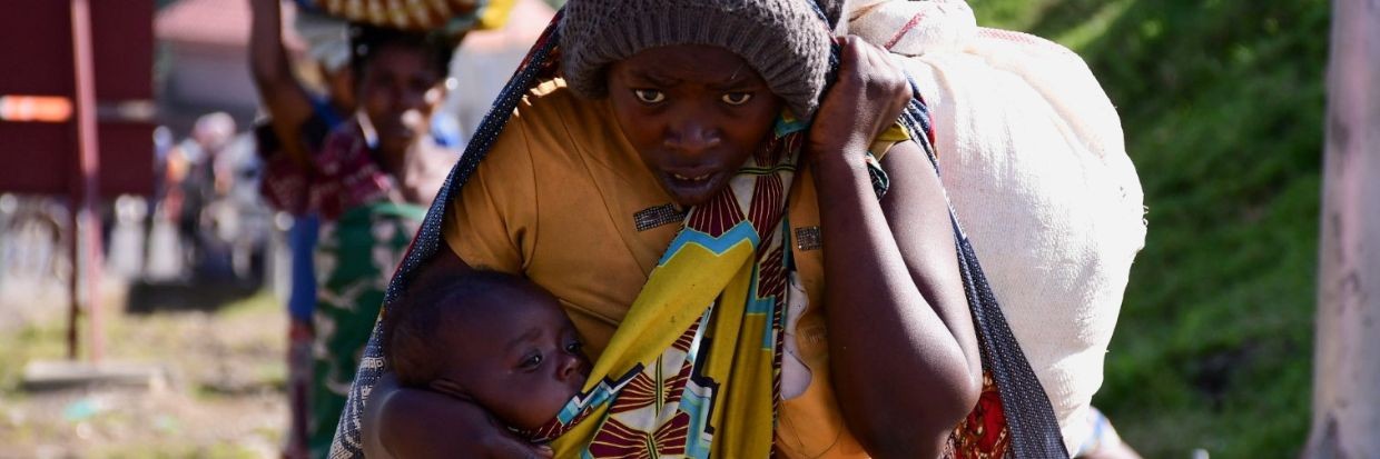 Une civile congolaise porte son enfant et ses affaires personnelles après avoir fui la reprise des combats entre les assaillants et les soldats de la République démocratique du Congo et de l’Ouganda, au point de passage frontalier de Bunagana situé dans l’ouest de l’Ouganda, le 10 novembre 2021.