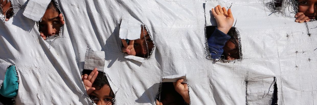 Children look through holes in a tent at al-Hol displacement camp in Hasaka governorate, Syria, April 2, 2019.© Reuters