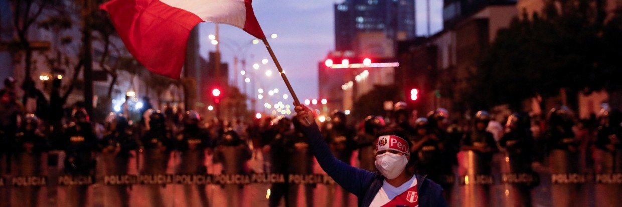 Un manifestante agita una bandera peruana mientras agentes de policía hacen guardia durante una protesta en Lima, Perú 11 de diciembre 2022. ©REUTERS / Alessandro Cinque