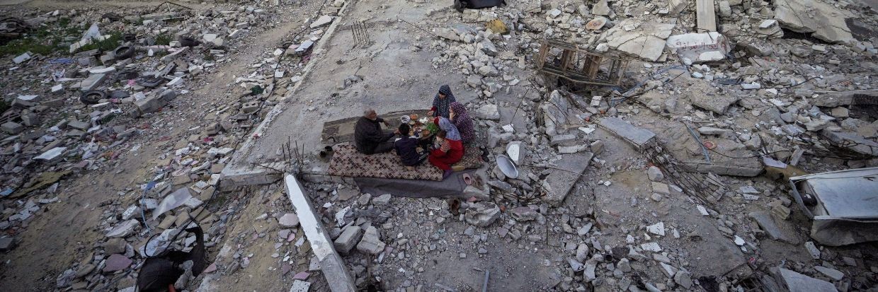 La famille palestinienne Al-Naji mange le repas de l’iftar, la rupture du jeûne, au milieu des ruines de leur maison familiale, le premier jour du mois de jeûne musulman du ramadan, à Deir el-Balah dans le centre de la bande de Gaza, le 11 mars 2024, alors que les combats se poursuivent entre Israël et le groupe militant du Hamas. © AFP