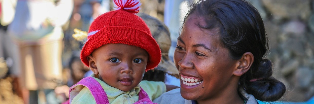 A woman smiling while holding an infant 