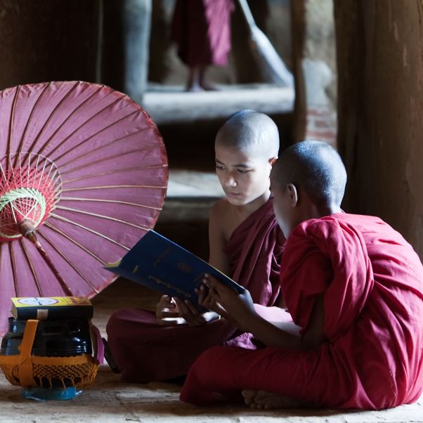 Two Buddhist monks reading a book inside the temple. © Getty Images