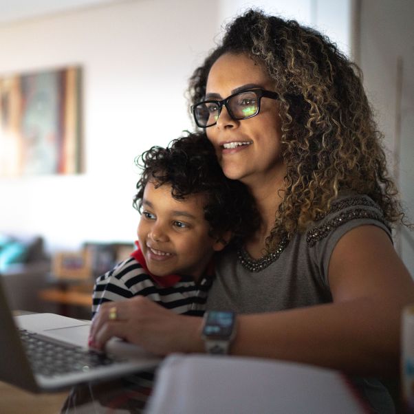 Mature woman working at home, carrying young son - stock photo. © Getty Images