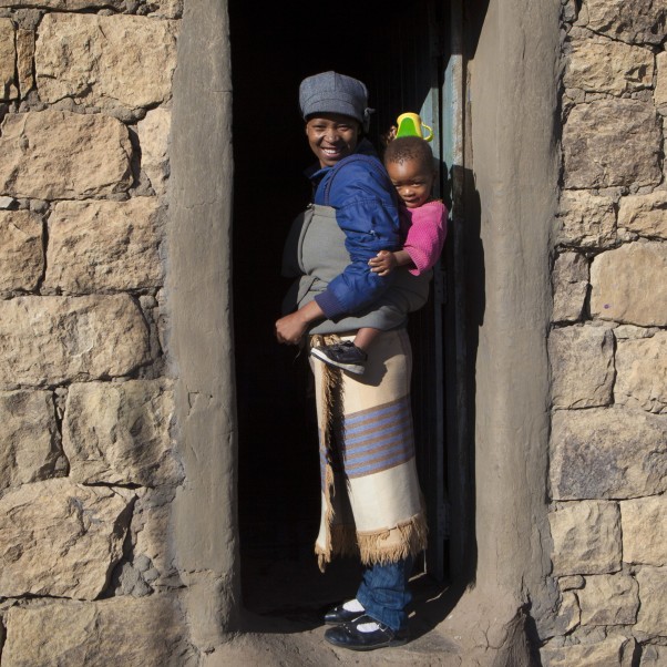 A mother carries a toddler on her backpack.