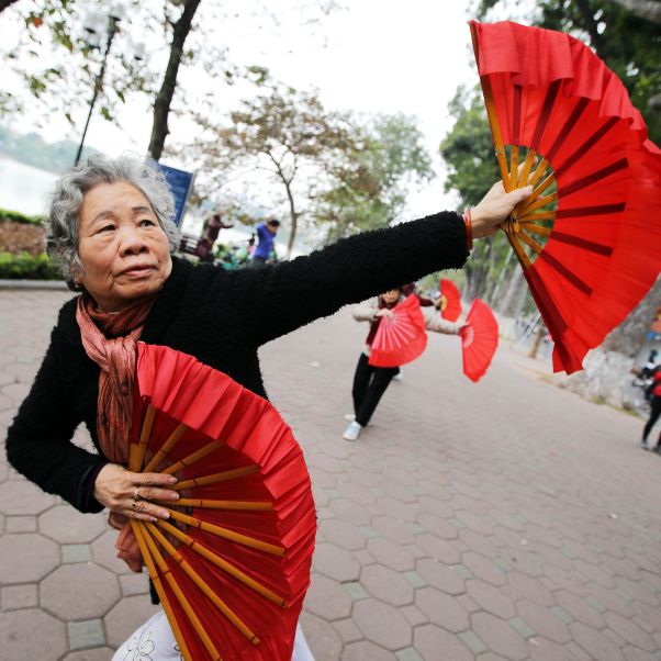 older woman performs a dance with fans