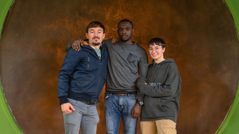 Three friends standing with their arms around one another