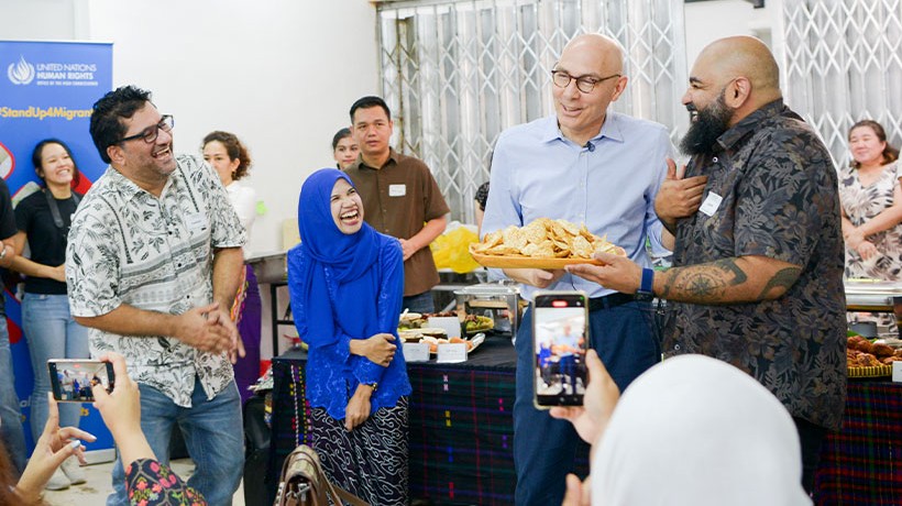 High Commissioner Türk is presented with a dish chosen for him by his migrant/refugee pair at the potluck lunch. Credit: © Dari Dapur