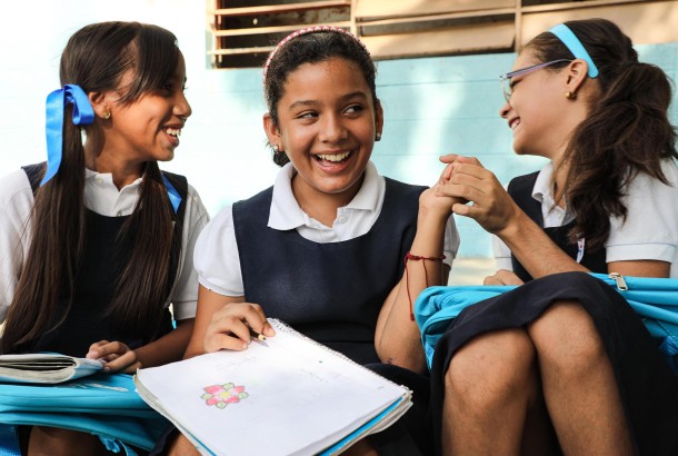 Three Venezuelan female students laughing together, 2019. © UNICEF/UNI220918/Orozco