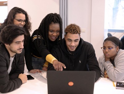 A group of people looking at a laptop screen together