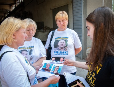 Ms Manukhina whose son and husband were detained by Russian soldiers shows photographs of her loved ones. © OHCHR/Yevhen Nosenko  