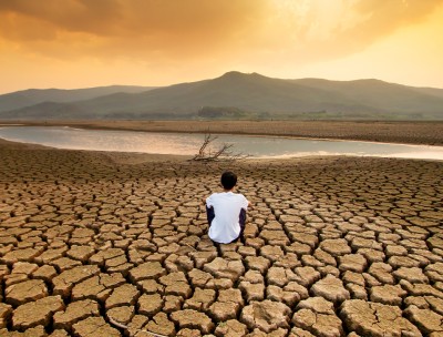 一个孩子坐在干涸的湖床上，头顶上的天空因污染而呈现出橘色。ISTOCK / GETTY IMAGES PLU