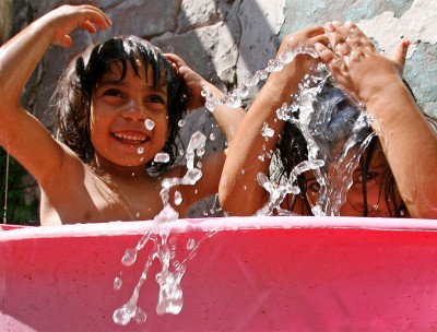 Roma children cool off in a tub of water in front of their house. © Credit –REUTERS/Ivan Milutinovic (SERBIA) 