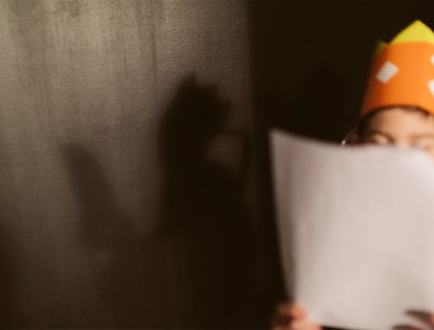 A child, whose face is hidden by a script he holds in his hands, during a theatre rehearsal. © Getty Images