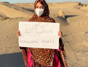 A girl carrying a sign "I Don’t Forward Hate"