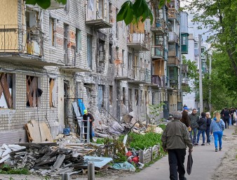 Locals walk past a residential building that was damaged during shelling in the outskirts of Kharkiv, Ukraine, 25 May 2022. © EPA-EFE/SERGEY KOZLOV