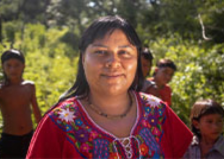 Ro’otsitsina Juruna standing in an open field with a group of children behind her. ©UNFPA